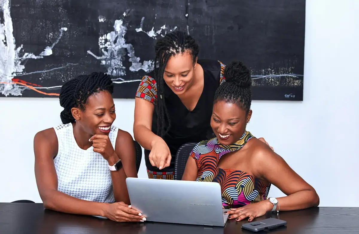 Three women working together around a laptop